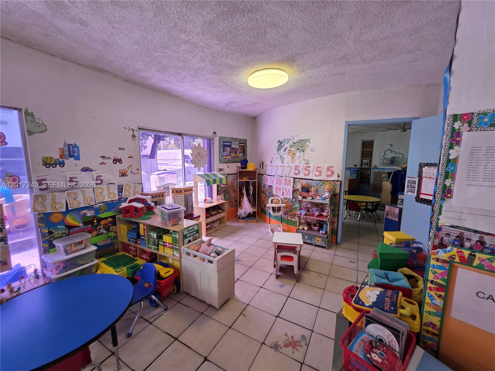 A brightly lit classroom features tiled floors, educational wall decorations, and various children's play equipment — 2660 SW 17th St, Miami FL 33145, MIAMI, FL