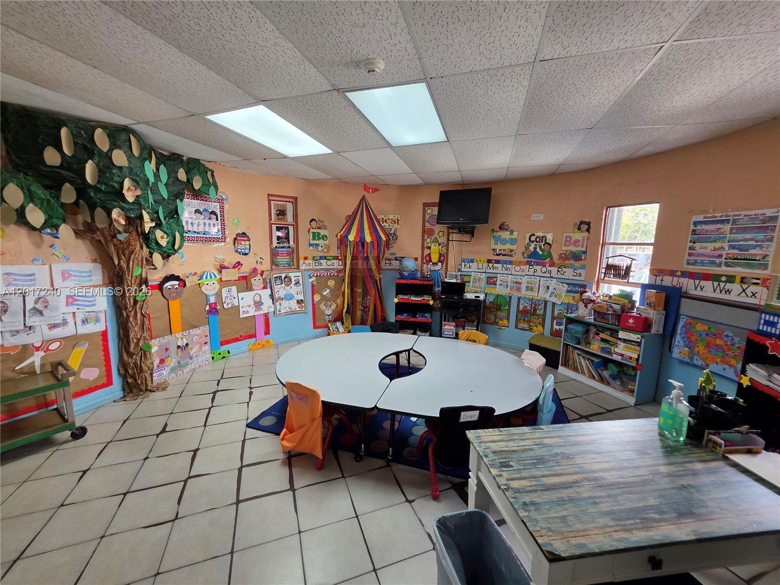 A colorful preschool classroom features a central round table, a decorative tree, and educational wall displays — 2660 SW 17th St, Miami FL 33145, MIAMI, FL