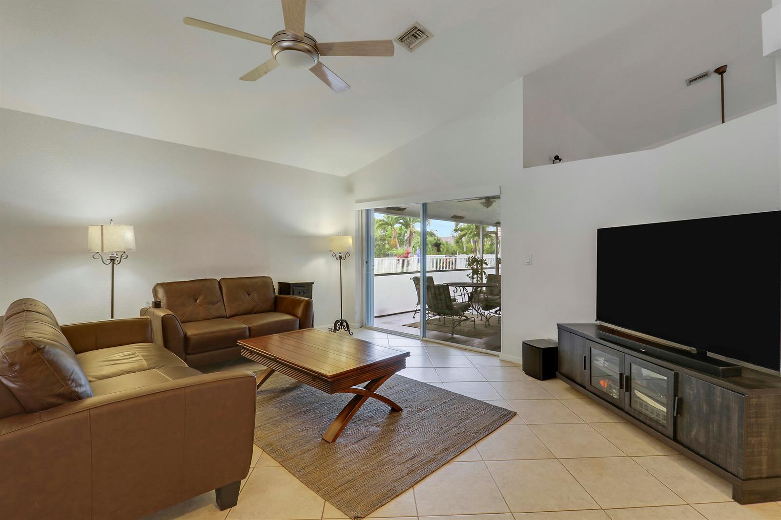 A living room features brown leather sofas, a wooden coffee table, and a large television — 7160 Brickyard Circle, Lake Worth FL 33467, LAKE WORTH, FL