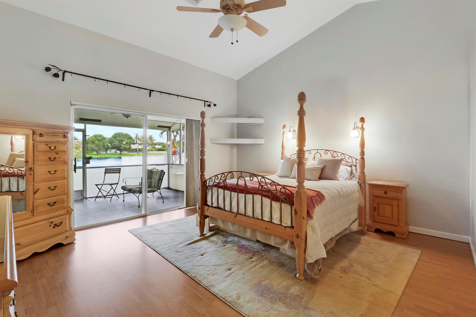 A bedroom features a four-poster bed, wood flooring, and a sliding door to a patio — 7160 Brickyard Circle, Lake Worth FL 33467, LAKE WORTH, FL