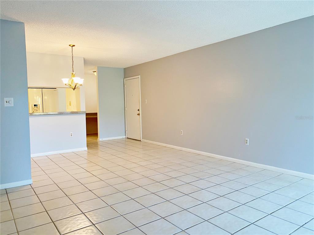 An open-concept living area features light-colored tile flooring, gray walls, and a kitchen pass-through — 2700 NEBRASKA AVENUE UNIT 5-105, PALM HARBOR, FL