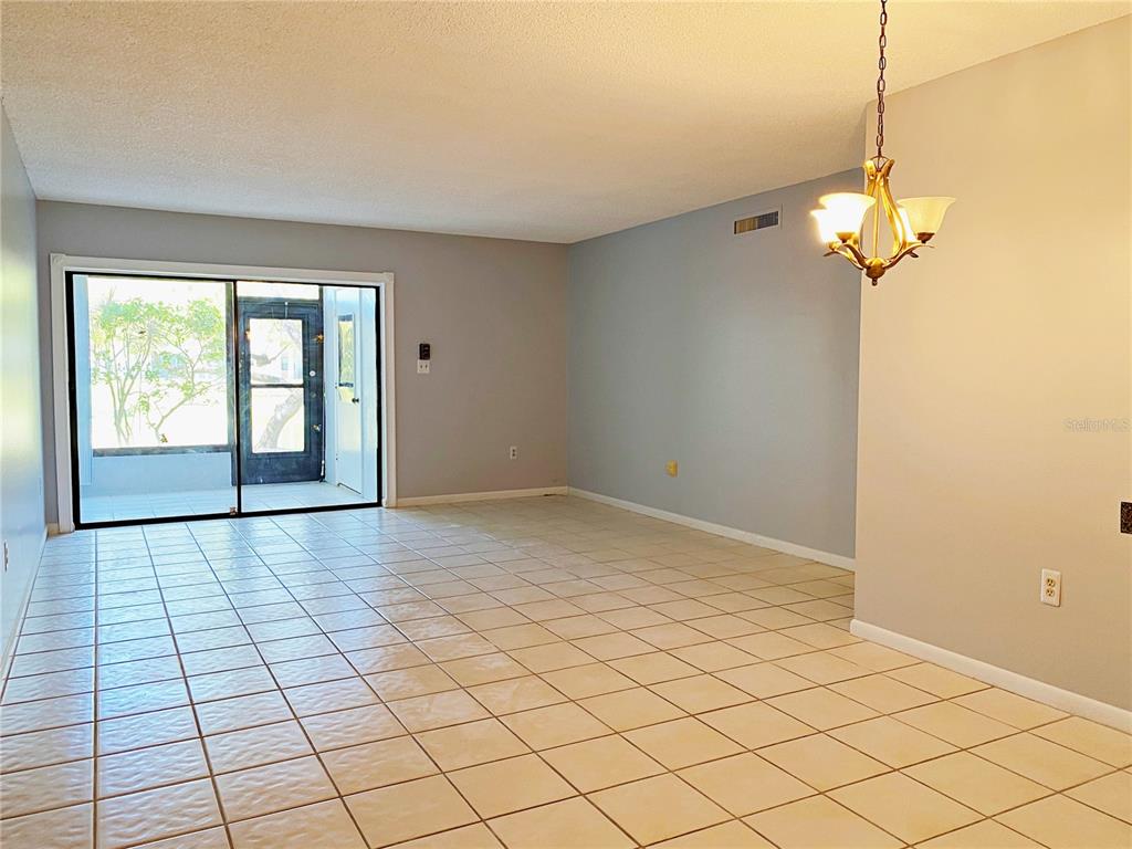 An empty room with light-colored tile flooring, gray walls, and a sliding glass door — 2700 NEBRASKA AVENUE UNIT 5-105, PALM HARBOR, FL