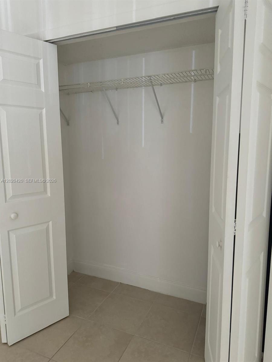 A closet with white double doors, a wire shelf, and light-colored tile flooring — 8275 SW 152nd Ave # 302, Miami FL 33193, MIAMI, FL