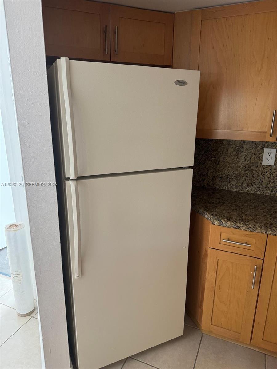 A white top-freezer refrigerator stands in a kitchen with wood cabinets and granite countertops — 8275 SW 152nd Ave # 302, Miami FL 33193, MIAMI, FL