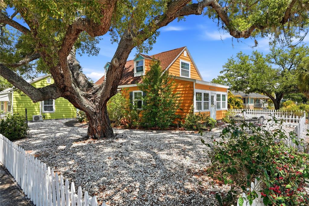 An orange house with a white picket fence and a large tree in the yard — 5407 29TH AVENUE S, GULFPORT, FL