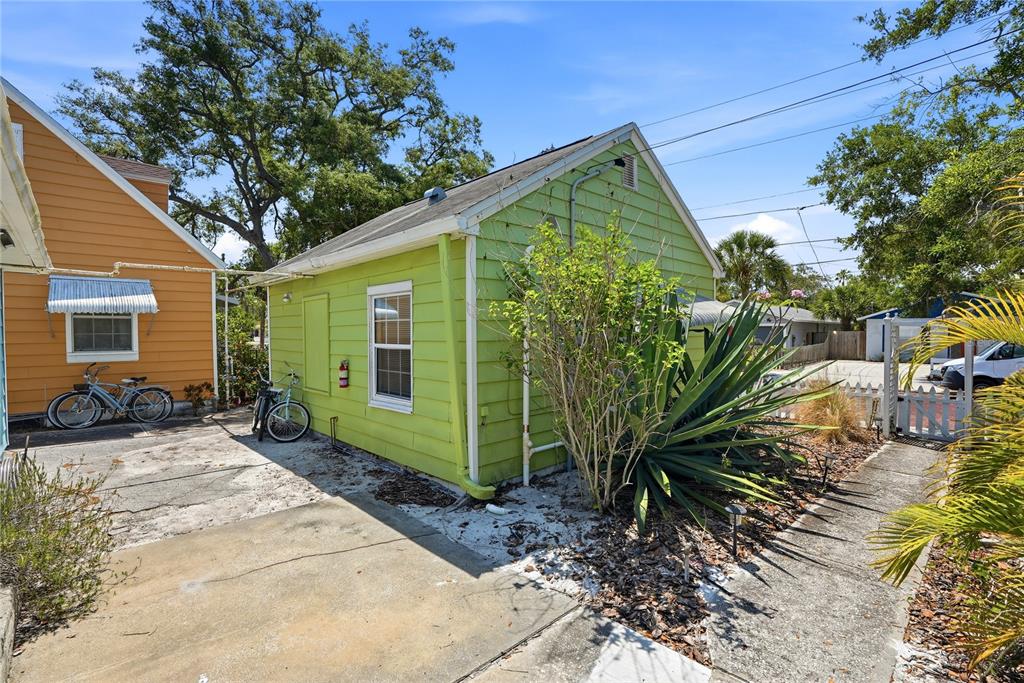 A lime green house exterior with a concrete driveway, a large plant, and two bicycles — 5407 29TH AVENUE S, GULFPORT, FL