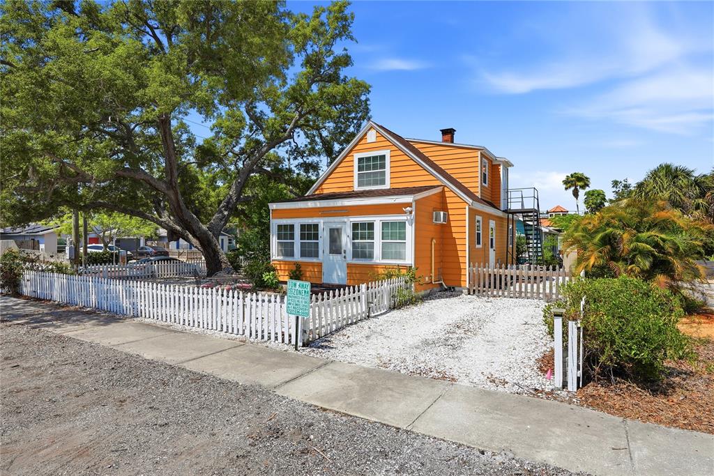 An orange two-story house with a white picket fence and a gravel driveway — 5407 29TH AVENUE S, GULFPORT, FL