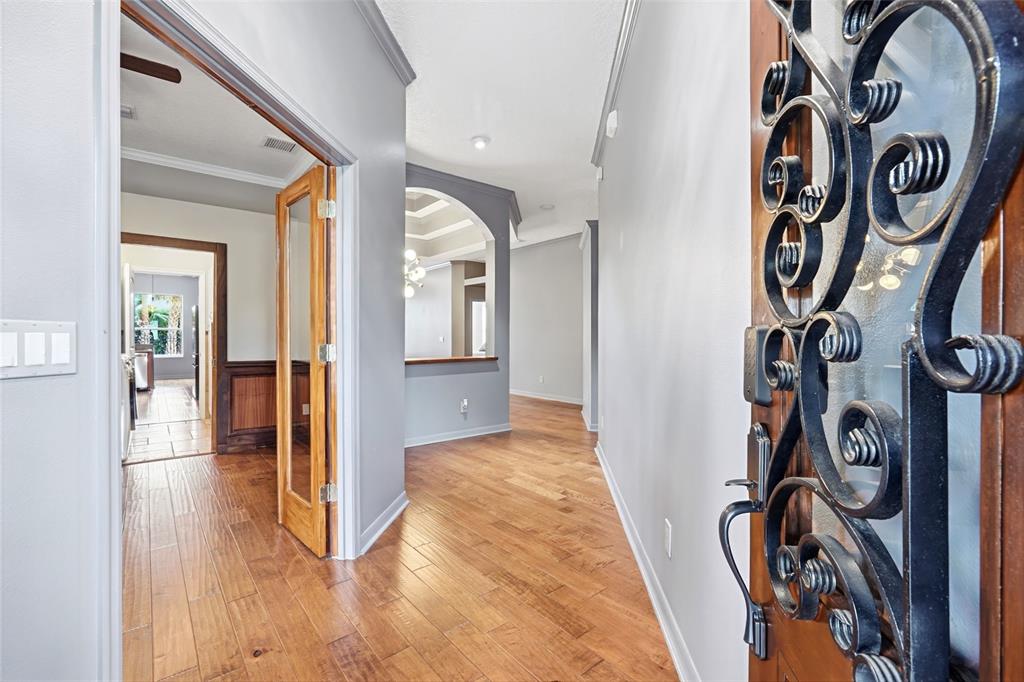 A hallway with hardwood floors leads to an arched opening and a glass-paneled door — 1707 COTTONWOOD CREEK PLACE, LAKE MARY, FL