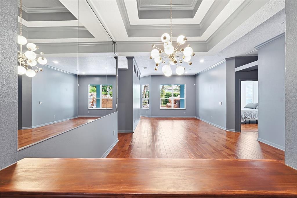 A room with hardwood floors, a large mirror, a modern chandelier, and a tray ceiling — 1707 COTTONWOOD CREEK PLACE, LAKE MARY, FL