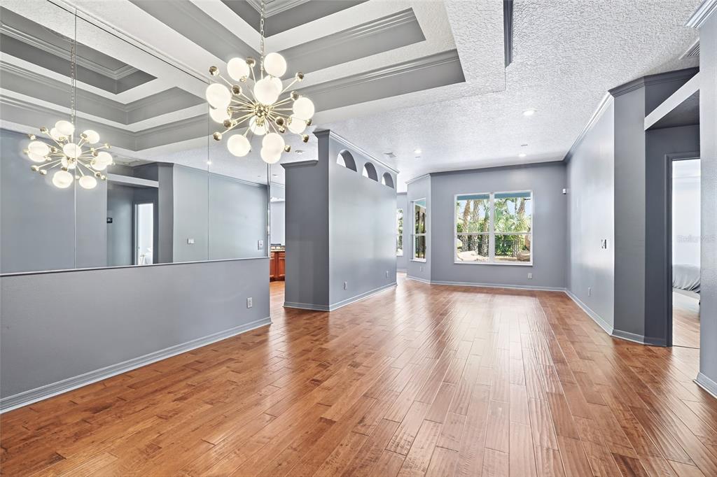 An empty room features hardwood floors, a modern chandelier, mirrored walls, and gray painted surfaces — 1707 COTTONWOOD CREEK PLACE, LAKE MARY, FL