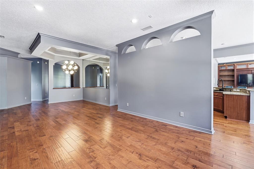 A spacious room with hardwood floors, a gray accent wall with arched cutouts, and mirrors — 1707 COTTONWOOD CREEK PLACE, LAKE MARY, FL