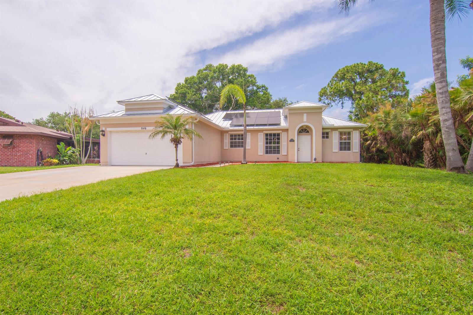 A single-story house with a metal roof, solar panels, and a front-facing garage — SEBASTIAN, FL