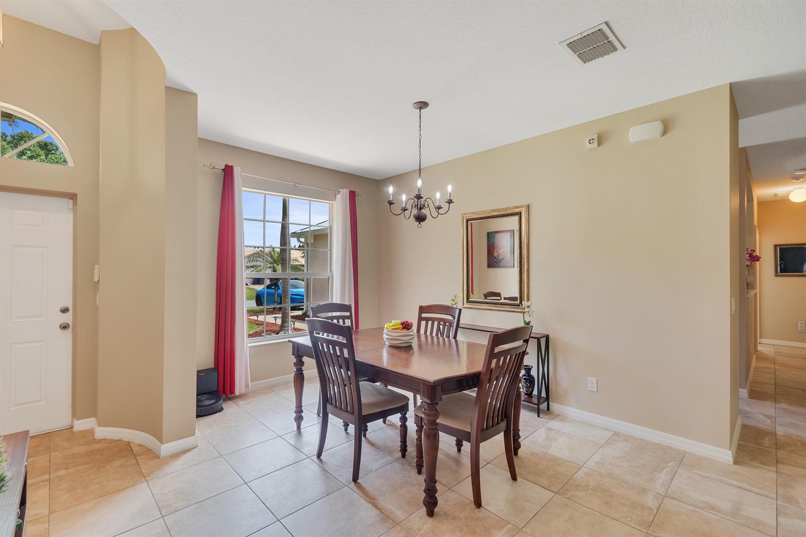 A dining room with tile floors, a wooden table, and a chandelier near a window — SEBASTIAN, FL