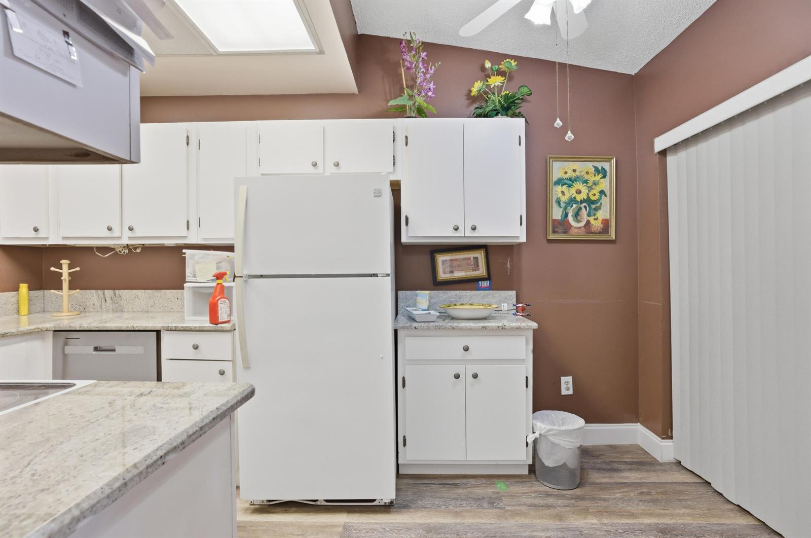A kitchen features white cabinets, granite countertops, a white refrigerator, and brown walls — 3582 Willa Way # B, Lake Worth FL 33467, LAKE WORTH, FL