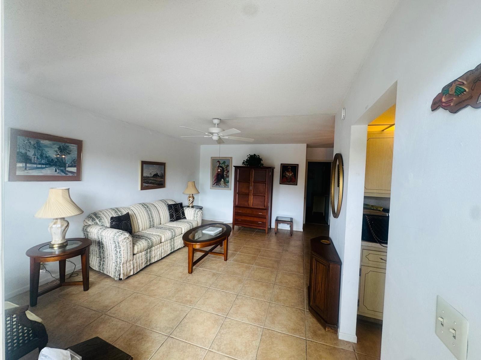 A living room with tile flooring, a striped sofa, and a wooden armoire — 2050 NE 39th Street # 209w, Lighthouse Point FL 33064, LIGHTHOUSE POINT, FL