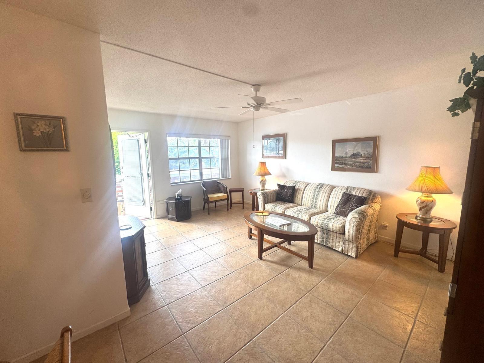 A living room features beige tile flooring, a striped sofa, and a glass-topped coffee table — 2050 NE 39th Street # 209w, Lighthouse Point FL 33064, LIGHTHOUSE POINT, FL