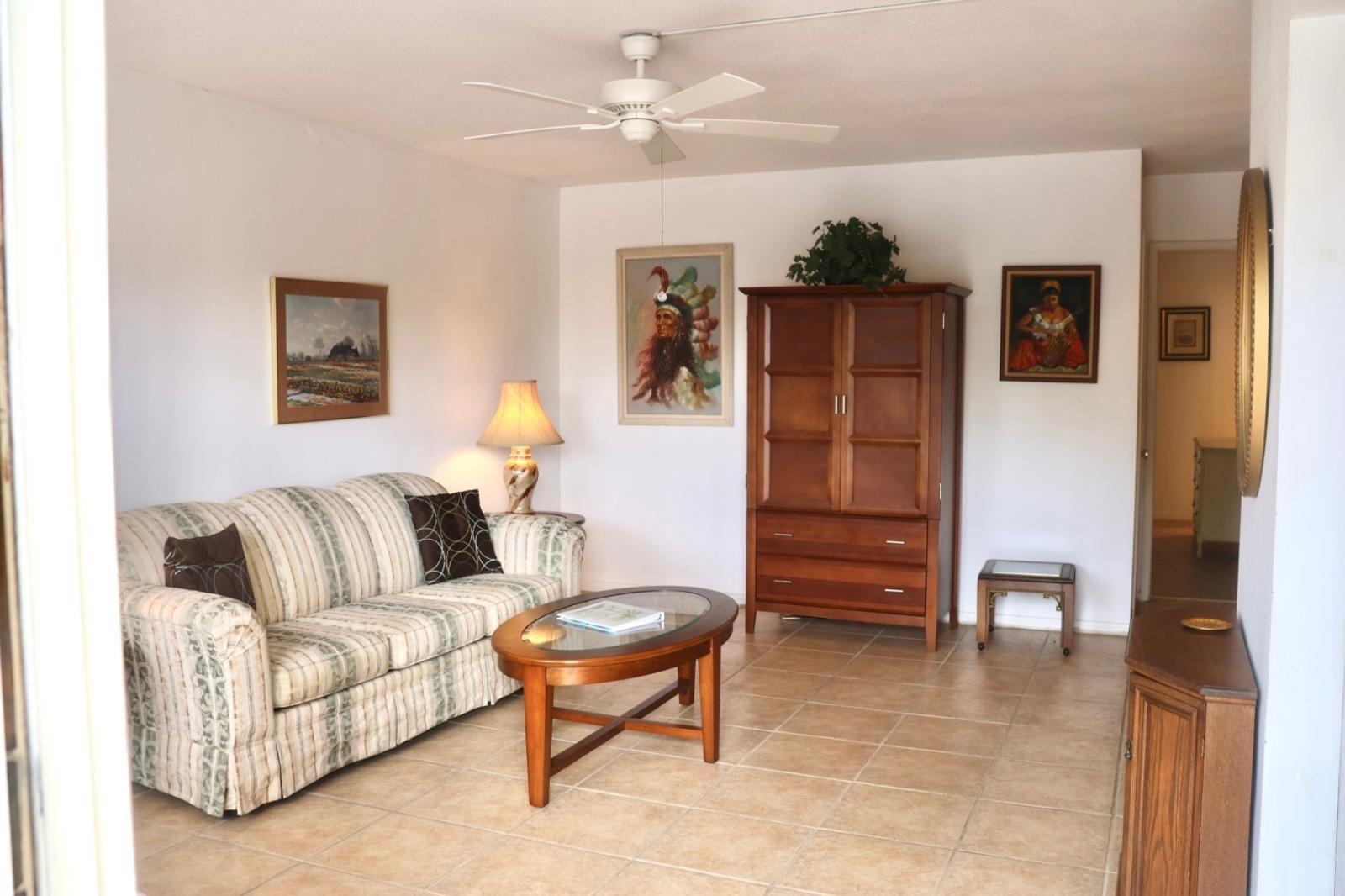 A living room with a striped sofa, wooden coffee table, armoire, and tile flooring — 2050 NE 39th Street # 209w, Lighthouse Point FL 33064, LIGHTHOUSE POINT, FL