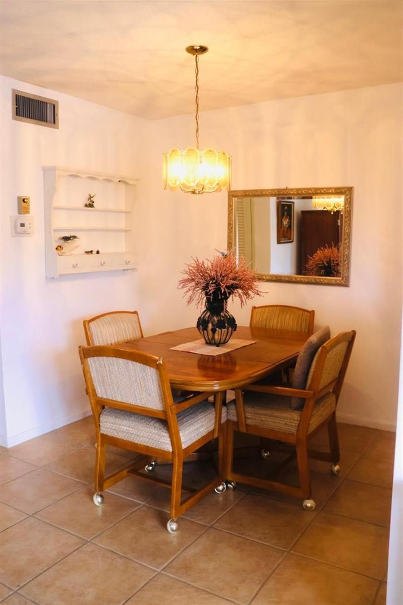 A dining area features a wooden table with four chairs, a chandelier, and a wall mirror — 2050 NE 39th Street # 209w, Lighthouse Point FL 33064, LIGHTHOUSE POINT, FL