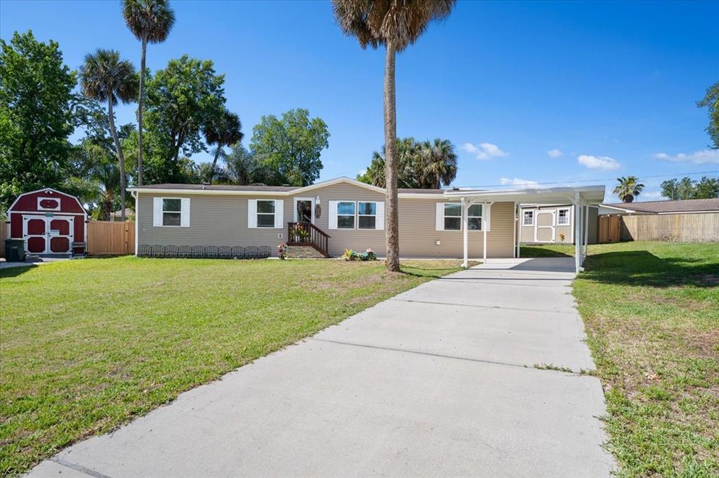 A single-story house with tan siding, a concrete driveway, a carport, and a storage shed — 1137 YAUPON STREET, DAYTONA BEACH, FL