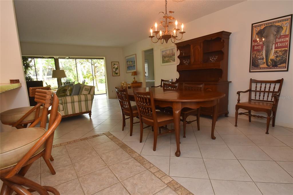 A dining area with a wooden table and hutch sits adjacent to a living room — 1703 PELICAN COVE ROAD UNIT GL356, SARASOTA, FL