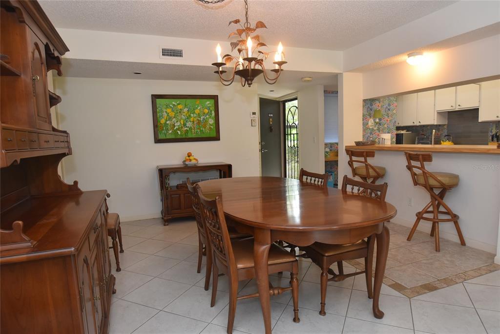 A dining room with a wooden table, chairs, hutch, and a breakfast bar with stools — 1703 PELICAN COVE ROAD UNIT GL356, SARASOTA, FL