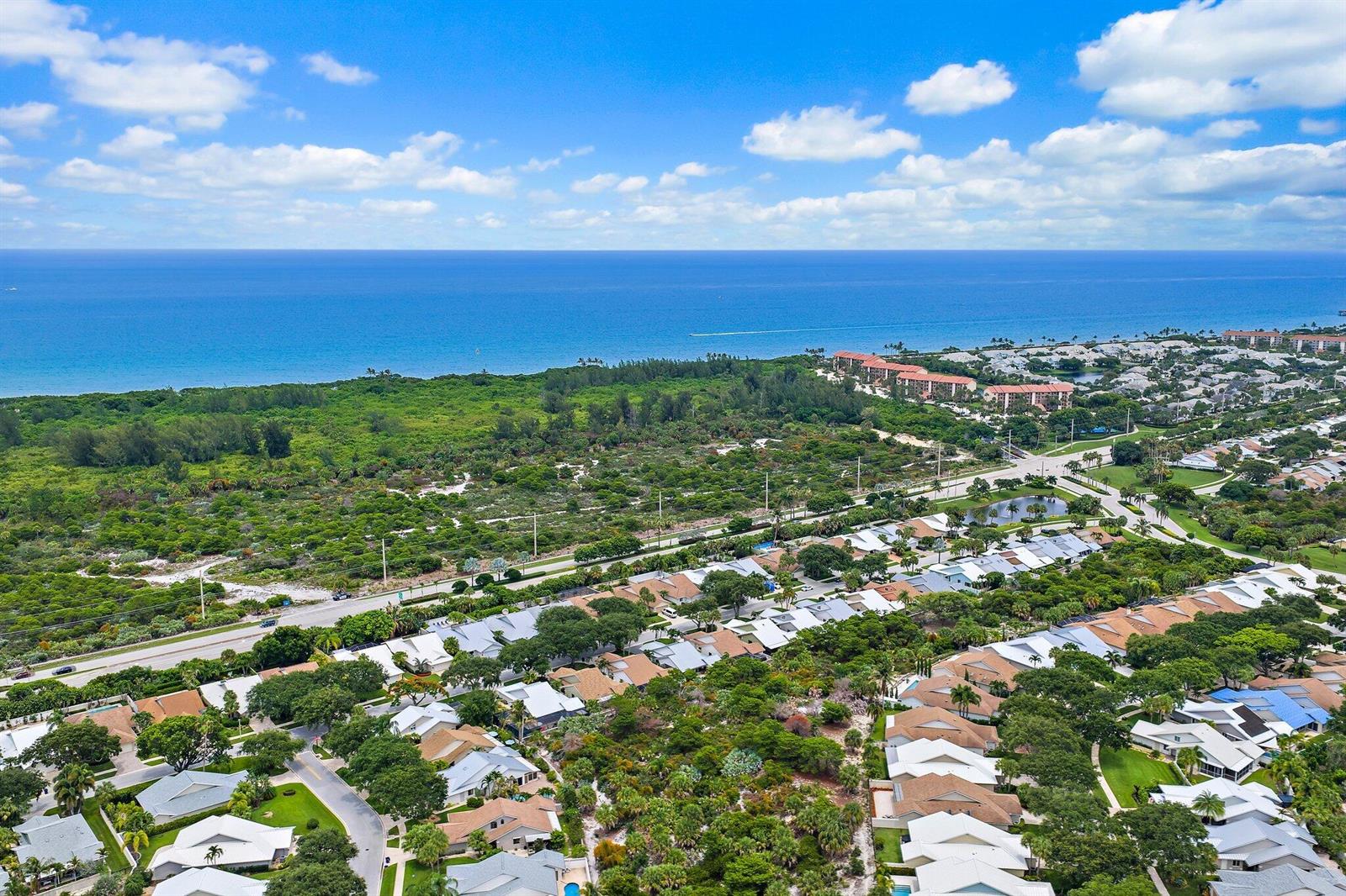 An aerial view shows a coastal residential neighborhood with houses, lush greenery, and the ocean — 126 Seashore Drive, Jupiter FL 33477, JUPITER, FL