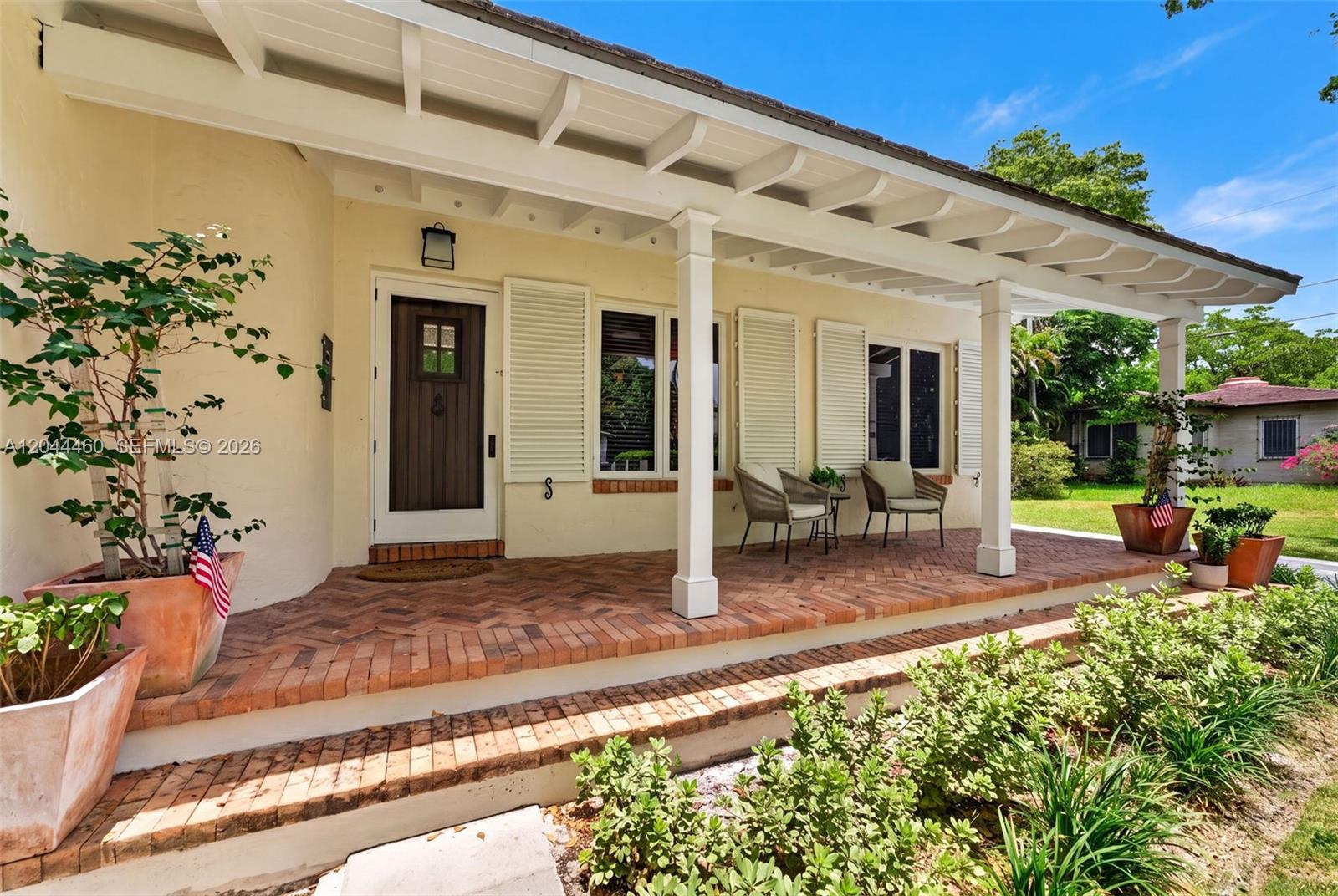 A house exterior features a brick porch, white columns, and a wooden front door — 1710 Segovia St, Coral Gables FL 33134, CORAL GABLES, FL