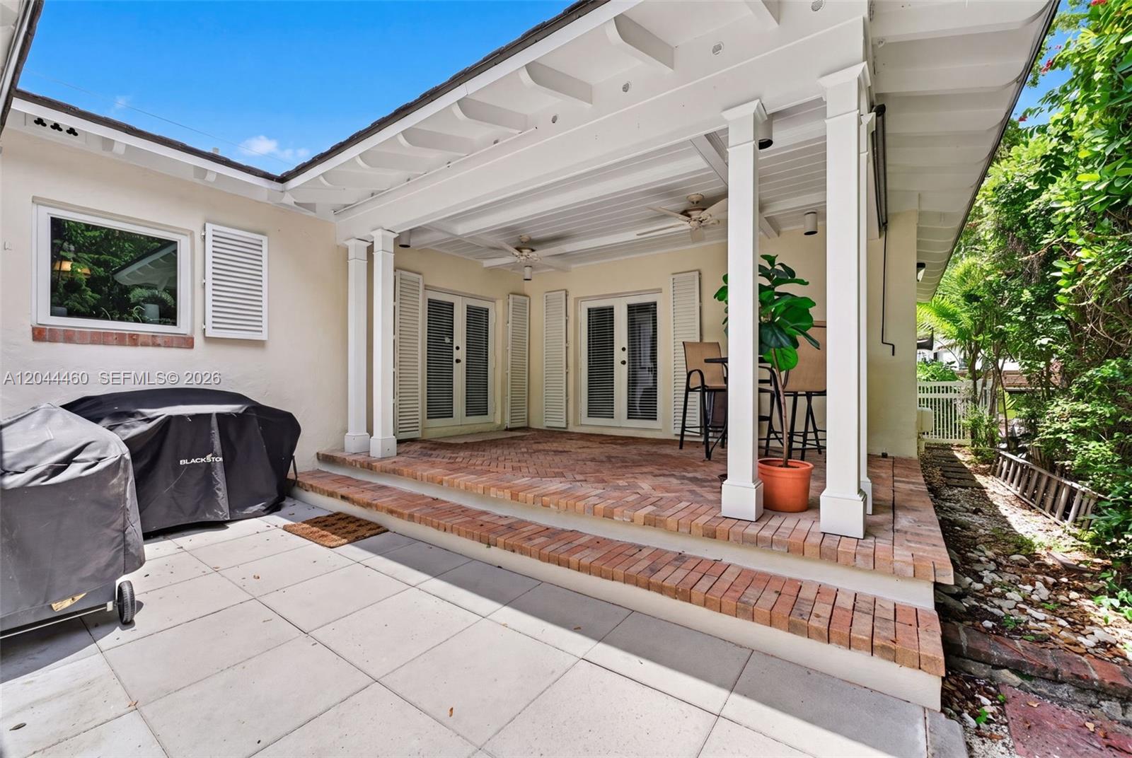 A covered brick patio features two sets of French doors and a grill area — 1710 Segovia St, Coral Gables FL 33134, CORAL GABLES, FL