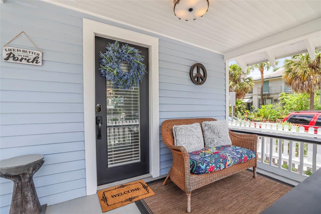 A light blue porch features a dark door, a wicker bench, and a welcome mat — 634 6TH STREET N, ST PETERSBURG, FL