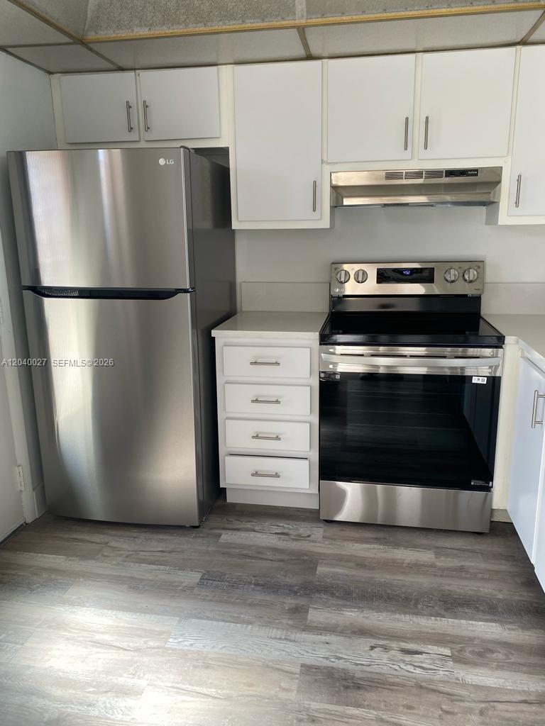 A kitchen features stainless steel appliances, white cabinets, and wood-look flooring — 406 NW 68th Ave # 526, Plantation FL 33317, PLANTATION, FL