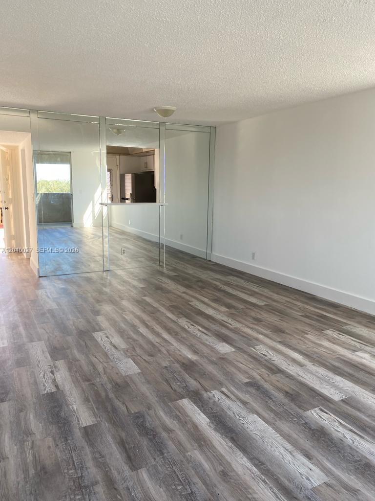 An empty room features wood-look laminate flooring, white walls, and a mirrored wall partition — 406 NW 68th Ave # 526, Plantation FL 33317, PLANTATION, FL