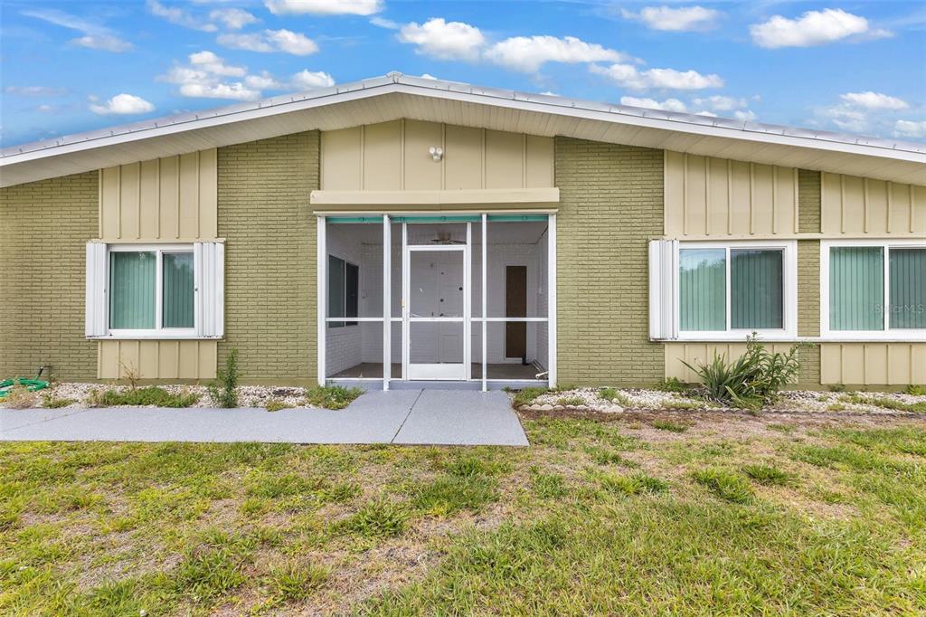 A single-story house with olive green brick siding, a screened-in porch, and white window shutters — 5527 FAIRWAY DRIVE S, PUNTA GORDA, FL
