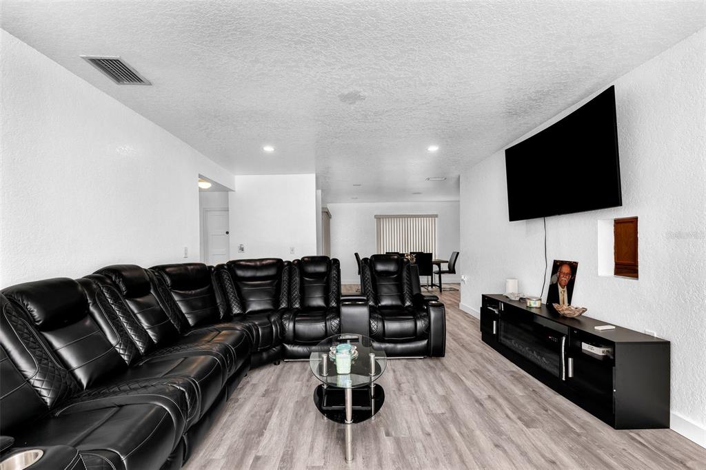 A living room features a large black sectional sofa, a glass coffee table, and a television — 5527 FAIRWAY DRIVE S, PUNTA GORDA, FL