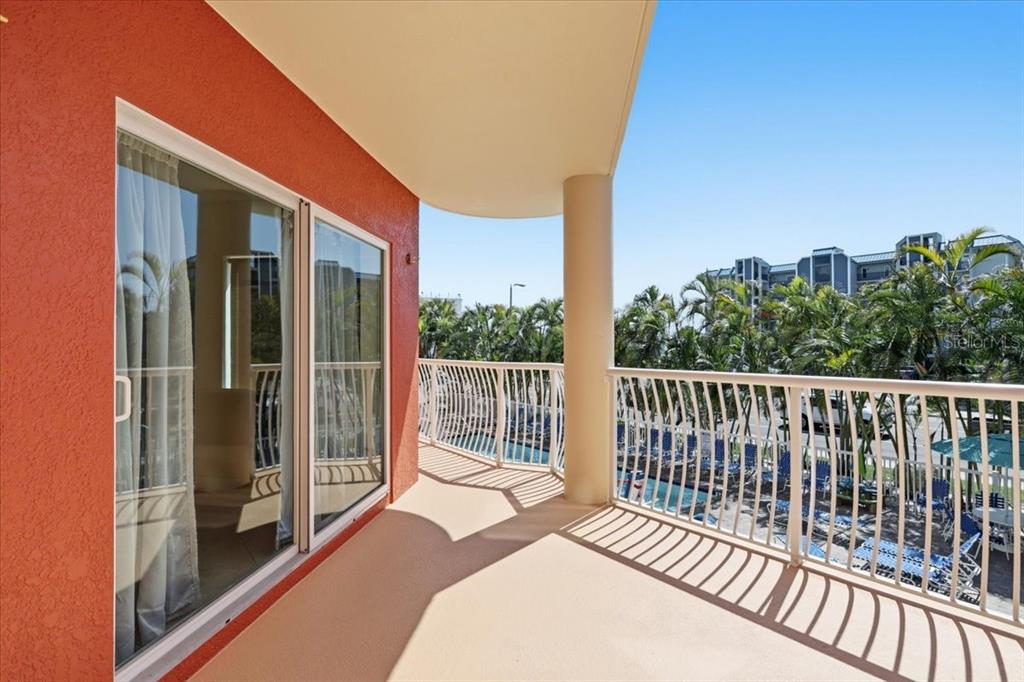 A balcony with a red wall, sliding glass doors, and a white metal railing — 11605 GULF BOULEVARD UNIT 206, TREASURE ISLAND, FL