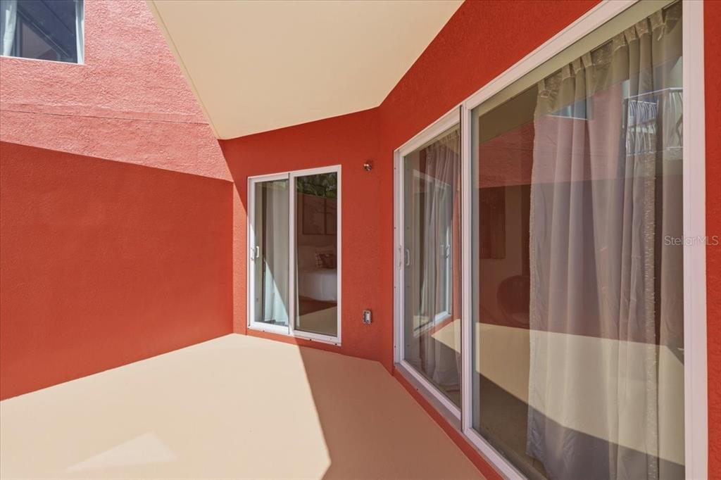 A covered patio with orange stucco walls and two sets of sliding glass doors — 11605 GULF BOULEVARD UNIT 206, TREASURE ISLAND, FL