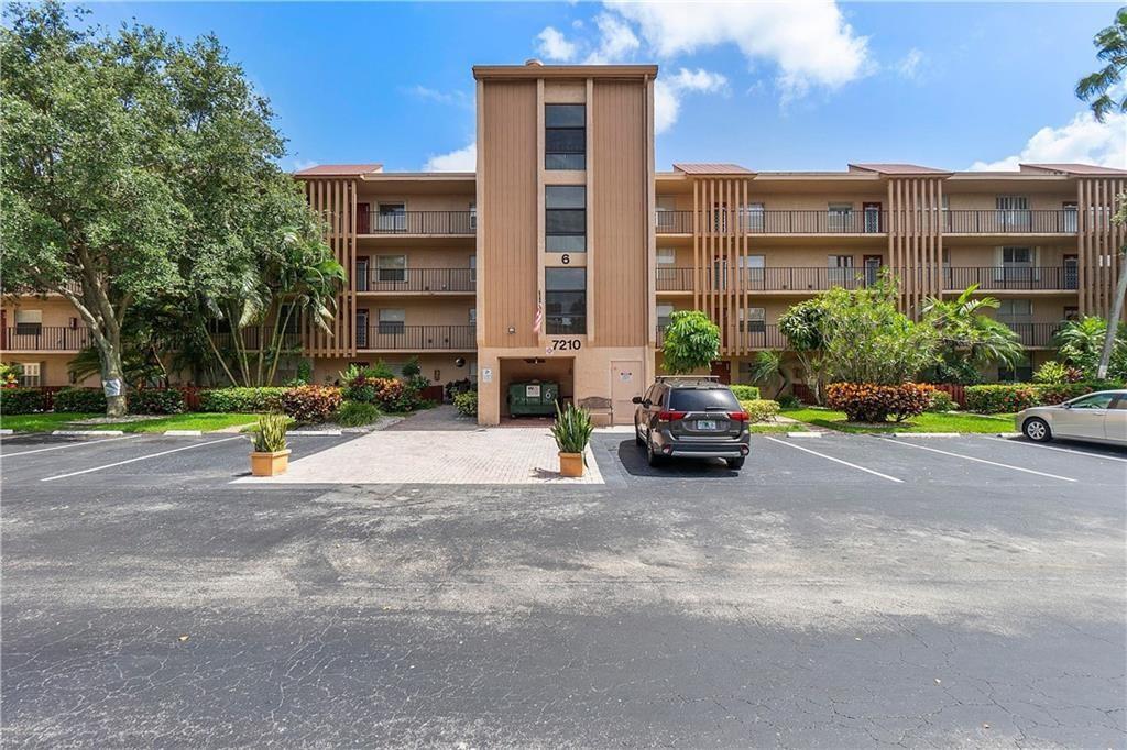 A three-story apartment building with a central entrance and a parking lot in front — 7210 Lake Circle Drive # 306, Margate FL 33063, MARGATE, FL