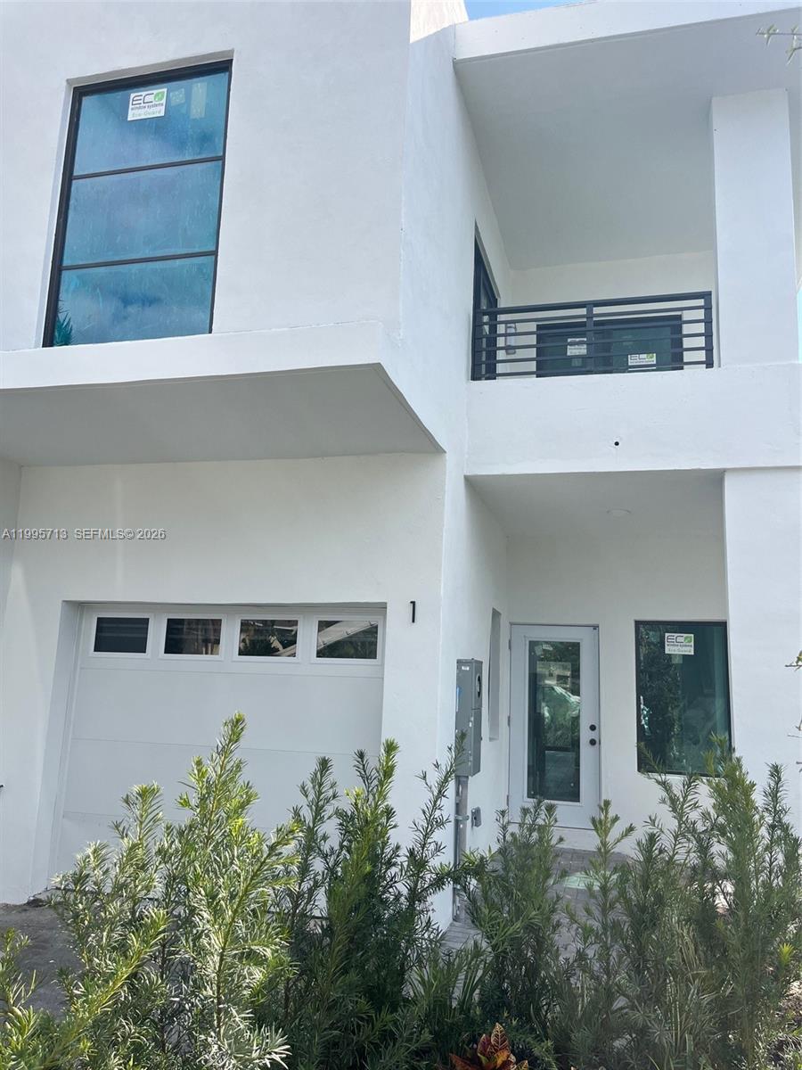 A modern two-story white house features a garage, a balcony, and large glass windows — 2511 Pierce St # 1, Hollywood FL 33020, HOLLYWOOD, FL