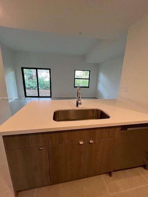 A kitchen island with a stainless steel sink and wood cabinets faces a living area — 2511 Pierce St # 1, Hollywood FL 33020, HOLLYWOOD, FL