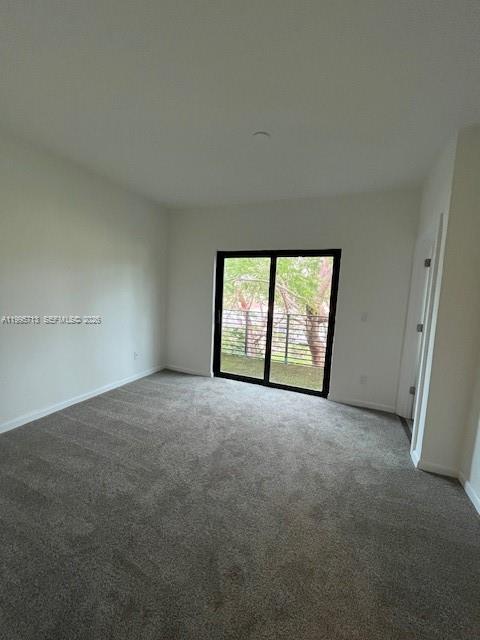 An empty bedroom features gray carpeting, white walls, and a sliding glass door to a balcony — 2511 Pierce St # 1, Hollywood FL 33020, HOLLYWOOD, FL