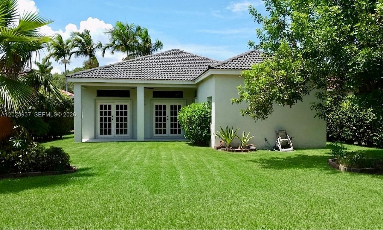 The exterior of a single-story house features a lawn, palm trees, and two glass doors — 953 Tanglewood Cir # 953, Weston FL 33327, WESTON, FL