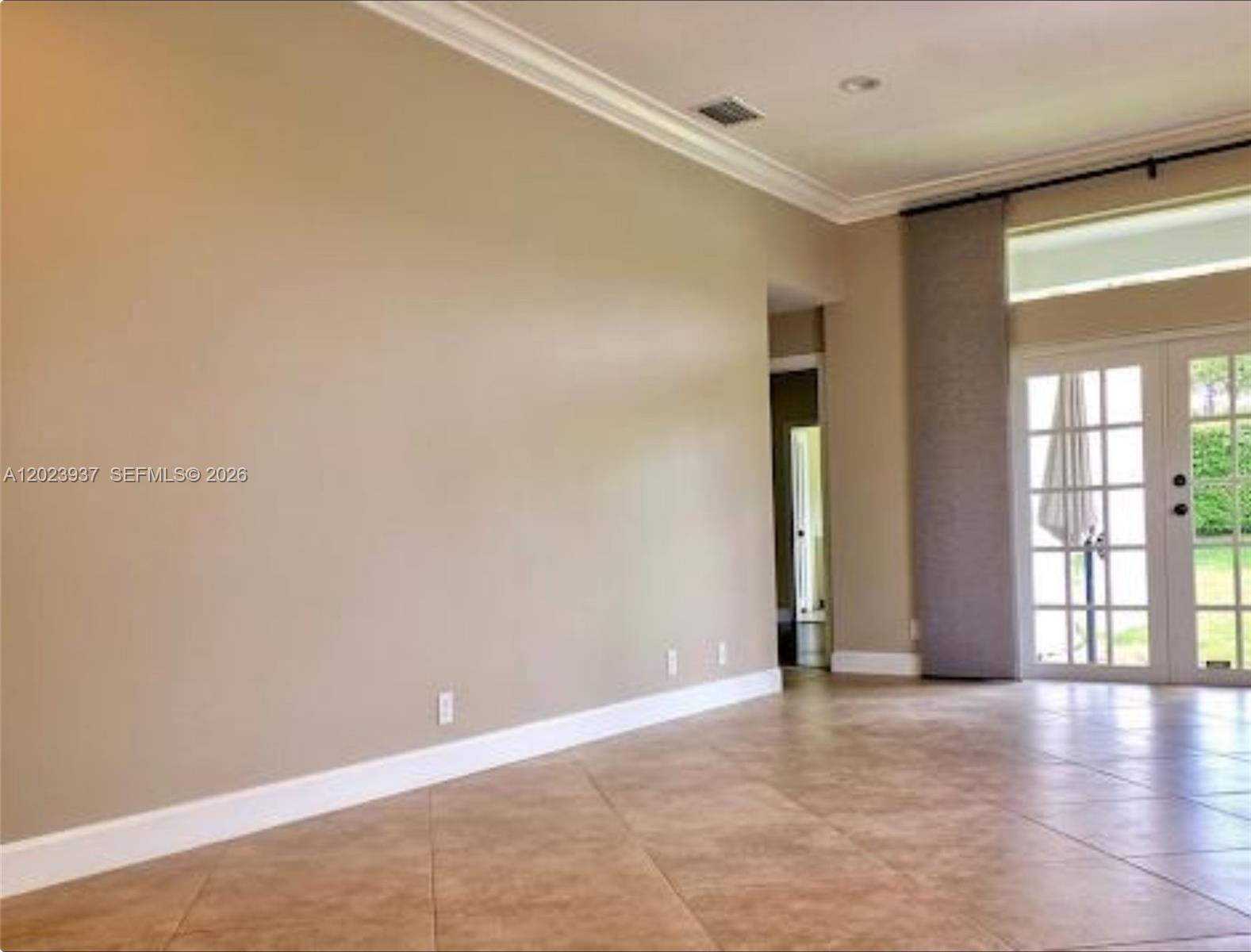 A spacious room features beige walls, tile flooring, crown molding, and glass French doors — 953 Tanglewood Cir # 953, Weston FL 33327, WESTON, FL