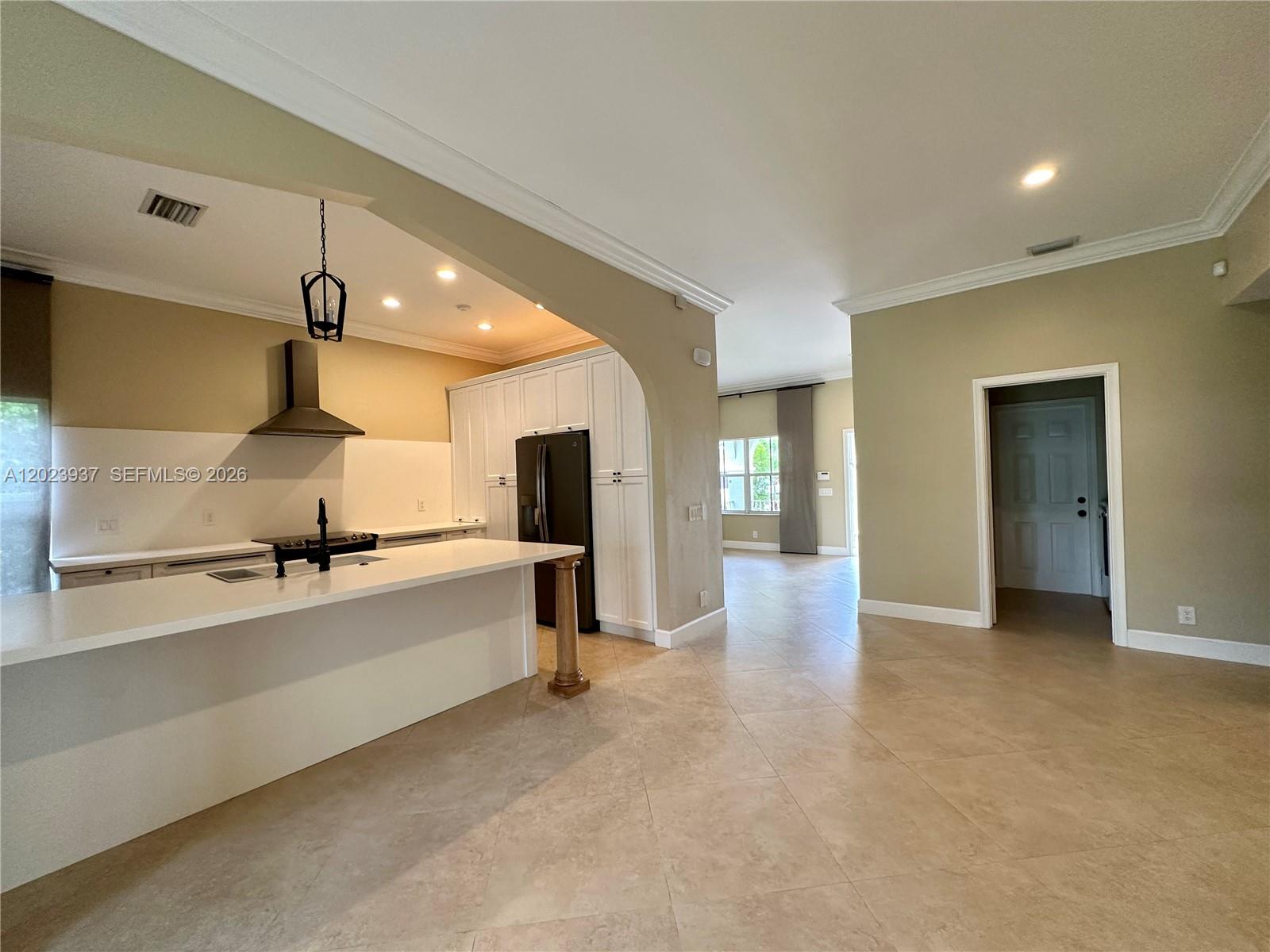 A kitchen with white cabinets and a breakfast bar opens into a living area — 953 Tanglewood Cir # 953, Weston FL 33327, WESTON, FL