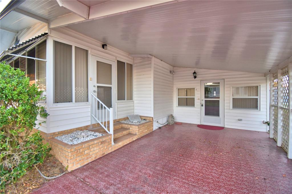 A covered carport area with a brick-bordered entrance, white siding, and two screen doors — 4251 CEDARWOOD STREET, WINTER HAVEN, FL