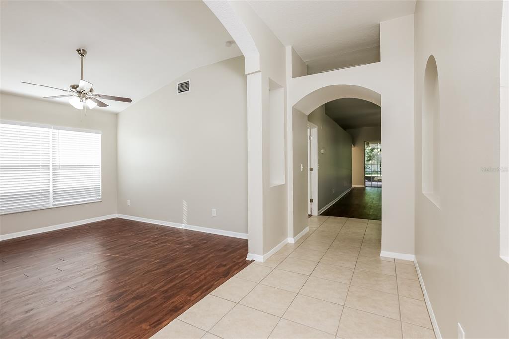 A living area with wood-look flooring transitions into a tiled hallway through an arched opening — 1717 ERIN BROOKE DRIVE, VALRICO, FL