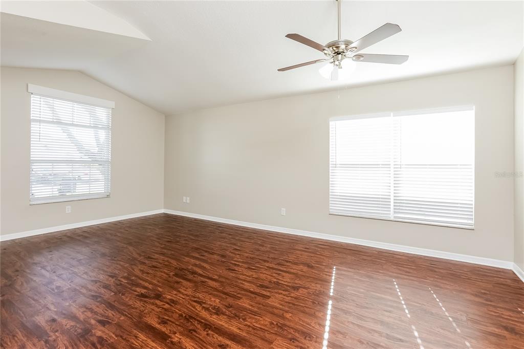 An empty room with wood-look flooring, beige walls, a ceiling fan, and two windows — 1717 ERIN BROOKE DRIVE, VALRICO, FL