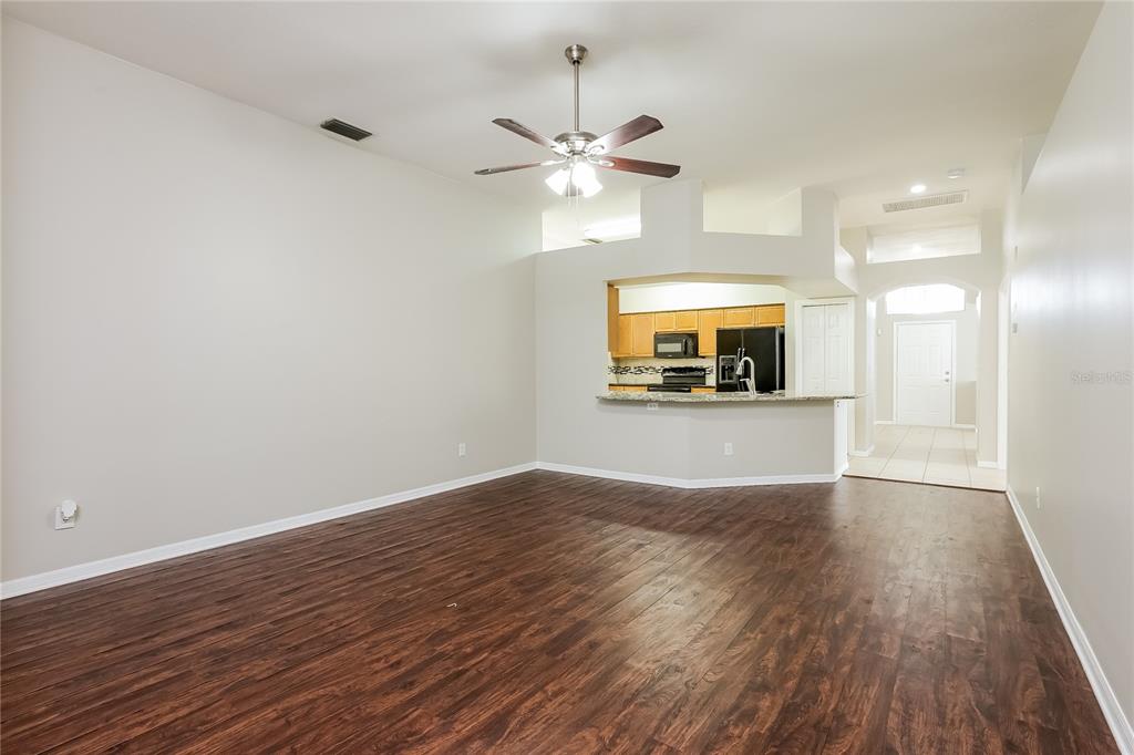 A living room with dark wood-look flooring, a ceiling fan, and an open kitchen pass-through — 1717 ERIN BROOKE DRIVE, VALRICO, FL