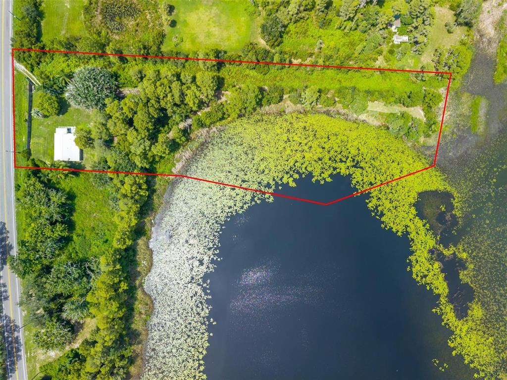 An aerial view shows a rectangular lot with a small house bordering a large lake — 10112 STATE ROAD 33, GROVELAND, FL