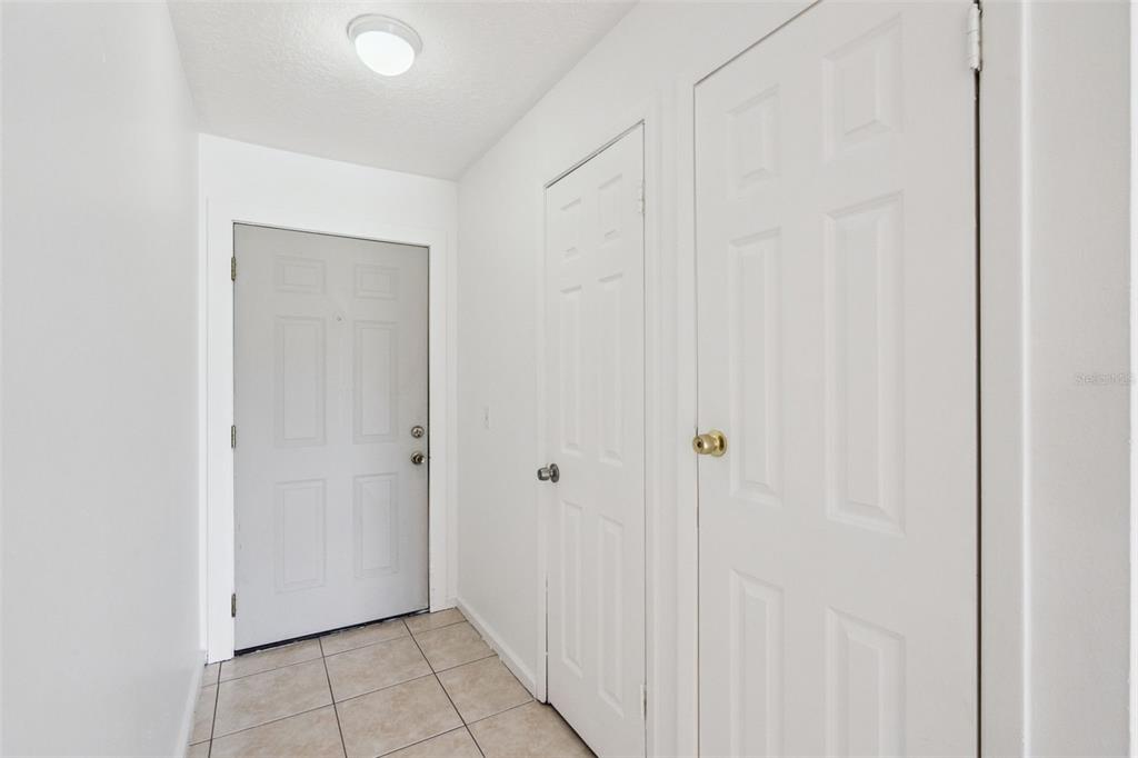 An entryway features a light gray door, two white closet doors, and tiled flooring — 6835 LONGMEADE LANE, ORLANDO, FL