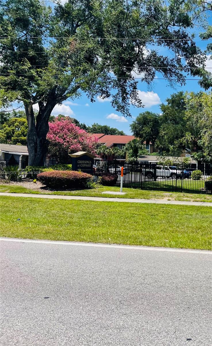 A black metal fence surrounds the Crossings at Conway apartment complex entrance with landscaping — 4251 E Michigan Street # 4251, Orlando FL 32812, ORLANDO, FL