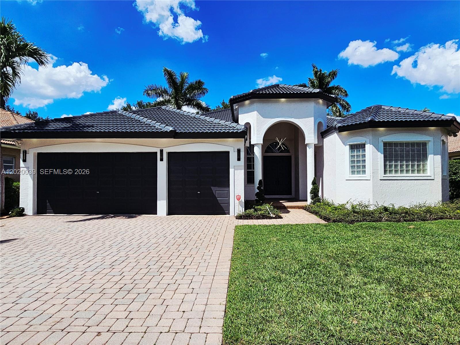 A single-story house with a dark tile roof, two garage doors, and a paved driveway — 18951 SW 30th St, Miramar FL 33029, MIRAMAR, FL